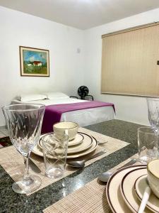 a room with a table with plates and glasses on it at Apart Cavalari Kitnets in Marília
