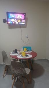 a table with chairs and a tv on a wall at Studio Figueira, Sol in Santarém