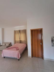 a bedroom with a bed and a couch and a door at Recanto das Rosas in Extrema