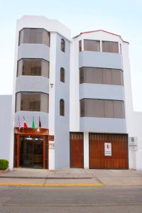 a tall white building with a red door at Hoteles Riviera Cayma in Arequipa