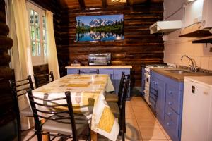 a kitchen with a table with chairs and a tv on the wall at Cabañas San Francisco in Potrerillos