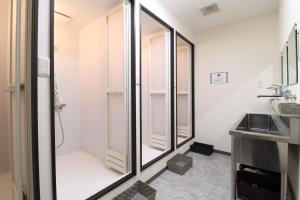 a bathroom with glass shower doors and a sink at SWELL in Hyuga +99 photos