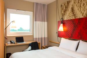 a hotel room with a bed and a desk with a laptop at ibis Cambrai in Cambrai