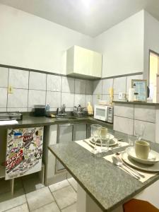 a kitchen with white cabinets and a table with glasses on it at Apart Cavalari Kitnets in Marília