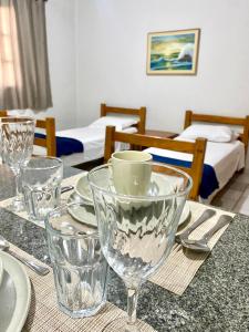a table with glasses and plates on a table with beds at Apart Cavalari Kitnets in Marília