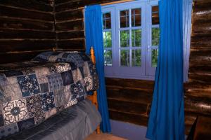 a bedroom with blue curtains and a window in a log cabin at Cabañas San Francisco in Potrerillos