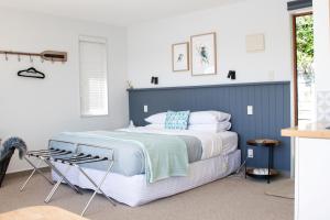 a bedroom with a large bed with a blue headboard at Picton Paradise Cottages in Picton