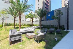 a patio with couches and chairs and palm trees at Studio Lumière Moema in São Paulo