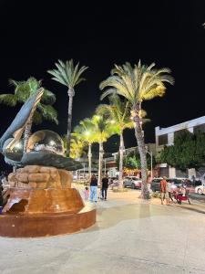 a statue in a square with palm trees at night at Private apartment La Paz baja in La Paz +10 photos