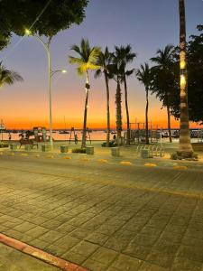 a street with palm trees and the beach at sunset at Private apartment La Paz baja in La Paz