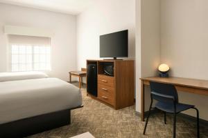a hotel room with a bed and a desk with a television at City Express by Marriott Danville in Danville