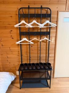 ein schwarzes Regal mit Kleiderbügeln und Schuhen darauf in der Unterkunft 最大4名の城ノ浜プール近くの宿 in Kihokucho + 19 Fotos