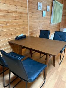 Ein Tisch und Stühle in einem Raum mit Holzwänden in der Unterkunft 最大4名の城ノ浜プール近くの宿 in Kihokucho