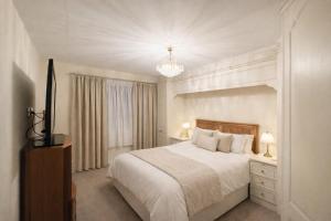 a white bedroom with a bed and a chandelier at Randall Farm Near Brands Hatch Circuit in Fawkham