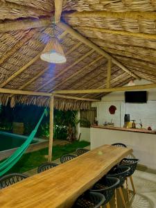 a large wooden table in a room with a hammock at Morada do Vento in Guriú