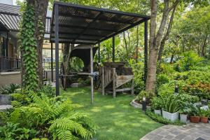 a garden with a pergola with a bench and plants at Rayong Valley Resort in Ban Khao Chak Khaek (1)
