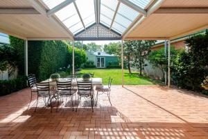a conservatory with a table and chairs on a patio at Peter Cottage - CBD Location, Bright & Homely in Wagga Wagga