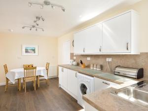 a kitchen with white cabinets and a table and a sink at Westburn in Comrie +16 photos