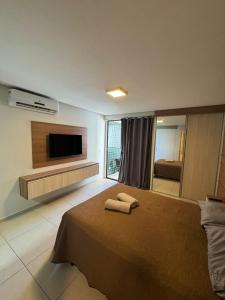 a bedroom with a bed and a flat screen tv at Flat beira mar Olinda Jam in Olinda