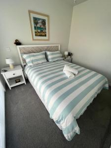 a bedroom with a blue and white striped bed at Sea Escape in Whitianga