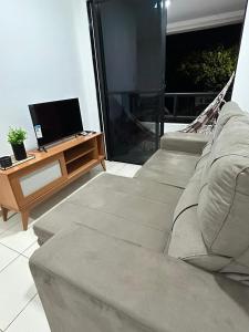 a living room with a couch and a television at Cantinho da Aruana, conforto e tranquilidade in Aracaju