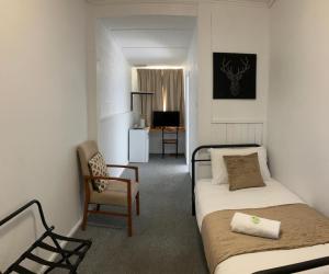 a small room with two beds and a chair at Berridale Inn in Berridale