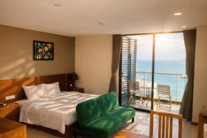 a bedroom with a bed and a green chair and a balcony at Holi Beach Hotel & Apartments in Nha Trang +248 photos
