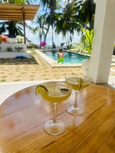 two cocktails sitting on a wooden table with a pool at Twin Palms Rote in Nembrala