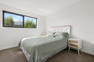 a white bedroom with a bed and a window at Coastal Ember in Inverloch