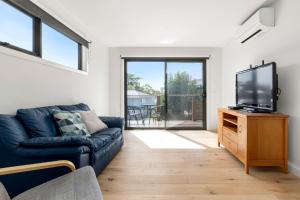 a living room with a couch and a flat screen tv at Coastal Ember in Inverloch