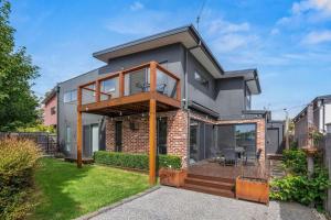 a modern house with a deck and patio at Coastal Ember in Inverloch