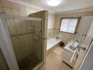 a bathroom with a shower and a tub and a sink at R&A Cottage in Windhoek +13 photos