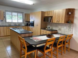 a kitchen with wooden cabinets and a table and chairs at R&A Cottage in Windhoek