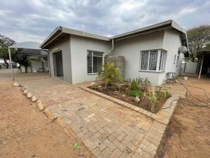 a house with a brick walkway in front of it at R&A Cottage in Windhoek