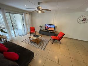 a living room with a couch and chairs and a tv at R&A Cottage in Windhoek