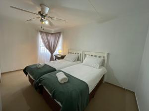 a bedroom with two beds and a ceiling fan at R&A Cottage in Windhoek