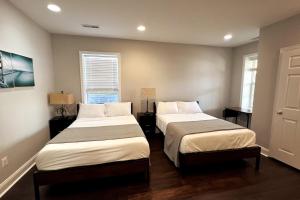 two beds in a room with two windows at 25 Lux Room 5 - 2 Queen Beds, Shared Bathroom - Nonsmoking in Arlington