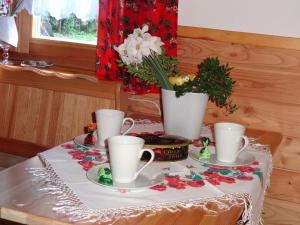 a table with cups and saucers and flowers on it at Camping Harenda Pokoje Gościnne i Domki in Zakopane