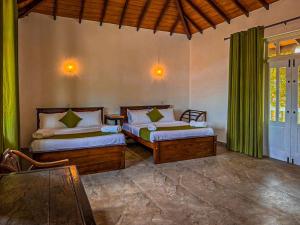 a bedroom with two beds and a table and a window at Nature Breeze Boutique Villa in Kandy