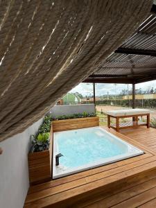 a hot tub on a wooden deck with a bench at Hotel La Libertad in Paipa