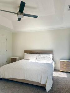 a white bedroom with a bed and a ceiling fan at Summerville’s Charm House in Summerville
