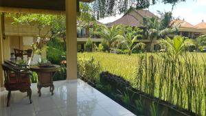 a porch with a table and chairs and a yard at Sri Aksata Ubud Resort in Ubud