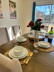 a table with plates and glasses and a vase of flowers at Summerville’s Charm House in Summerville