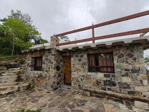 an old stone house with a wooden door at Cabañas El Amanecer in Cuetzalán del Progreso
