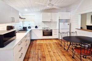 a kitchen with white cabinets and a table and chairs at A Warm & Charming Retreat in Castlemaine