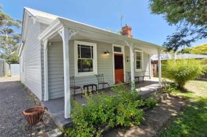 a small white house with a porch and chairs at A Warm & Charming Retreat in Castlemaine