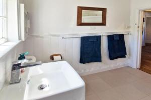 a bathroom with a white sink and blue towels at A Warm & Charming Retreat in Castlemaine +6 photos