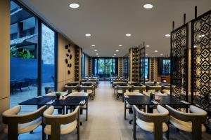 a restaurant with tables and chairs and windows at Myze Hotel Waingapu in Waingapu