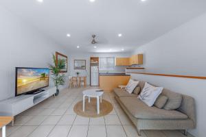 a living room with a couch and a tv and a kitchen at PET FRIENDLY Coolview in Cannonvale