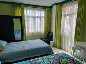 a bedroom with a bed and a chair and windows at Casa Danna in Sucre
